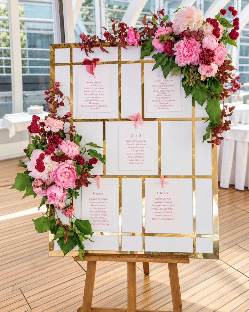 Seating plan con flores rosas y burdeos sobre estructura dorada para bodas y eventos — Flores MERAKI Tenerife