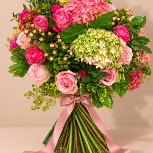 Ramo Elegancia Natural con rosas y hortensias sobre una mesa beige, con cintas rosas y sombra natural
